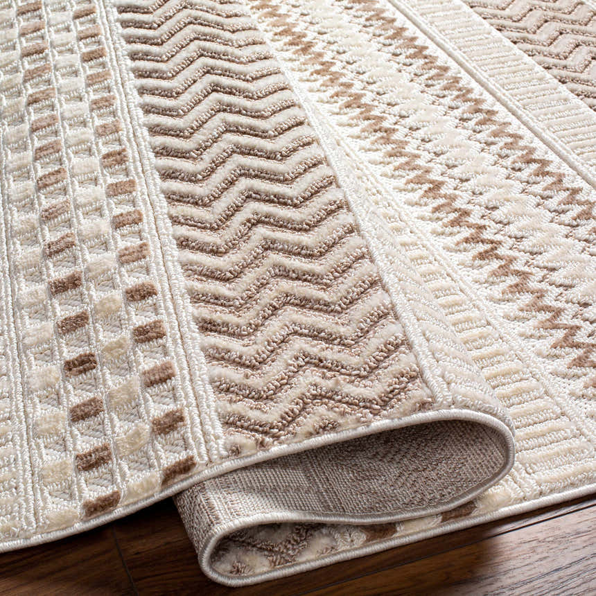 Close-up of the Eiko Beige Textured Saxony Rug showing geometric patterns and soft bone, driftwood, and nutmeg colors. Fold