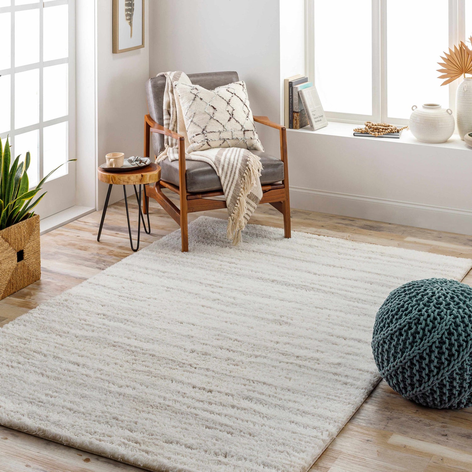 Cozy living room scene with a cloud gray Ajeya Area Rug, gray chair, and sage green pouf. Roomscene-Rectangle