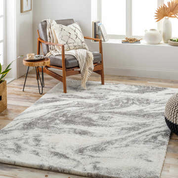 Cozy living room scene with a gray chair and a light gray and white Delma Area Rug. Roomscene-Rectangle
