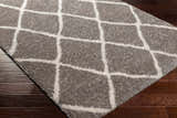 Close-up of the Faye Area Rug, a gray shag rug with a geometric off-white diamond pattern. Corner
