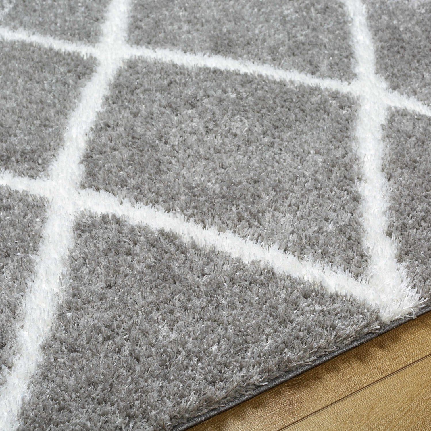 Close up of the Faye Area Rug featuring a gray shag texture and a white geometric pattern. Texture