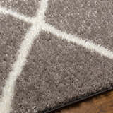 Close-up of Faye Area Rug showing charcoal shag texture and off-white geometric pattern. Texture