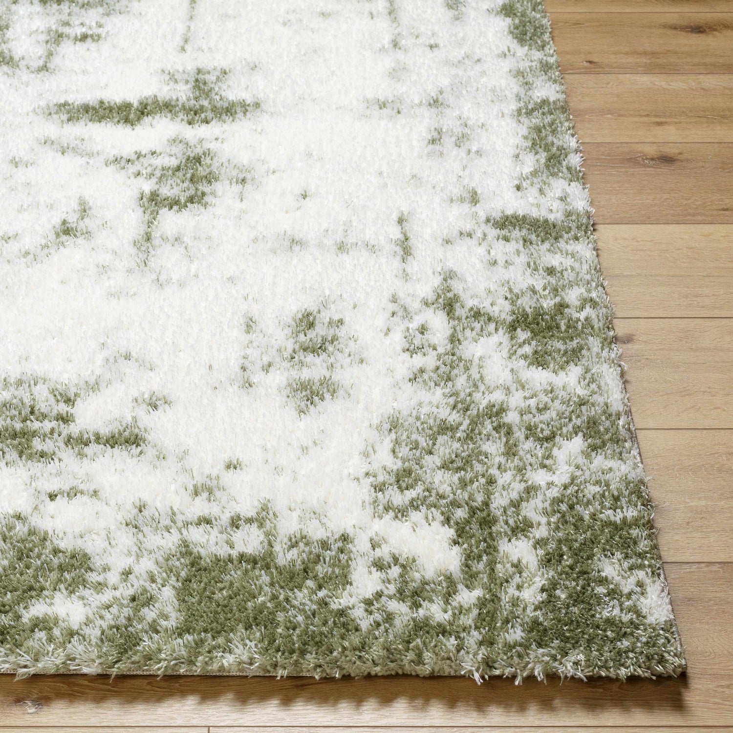 Close-up of the plush Jioni Area Rug in beige and bone with a shag texture on light wood flooring. Front