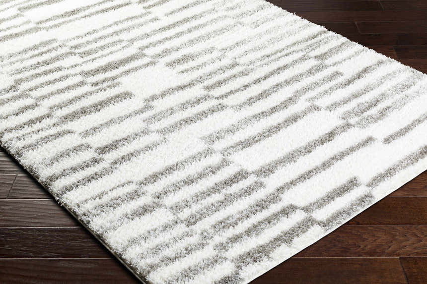 Close-up of the Kuron Area Rug, a shag rug with a contemporary gray and off-white geometric design. Corner