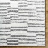 Close-up of the Kuron Area Rug showing its charcoal and off-white shag stripes and soft, textured pile. Corner