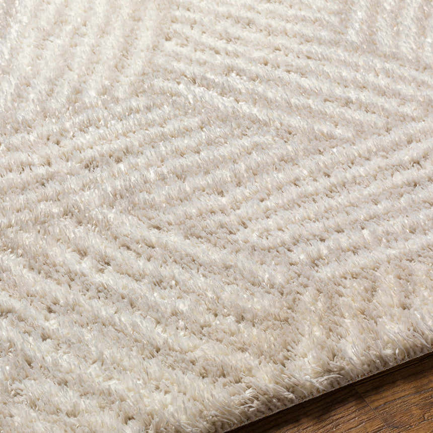 Close up of the Mura Cream Area Rug showing its shag texture and geometric pattern. Texture