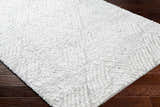 Close-up of the plush Mura Gray Area Rug showing off white shag texture and geometric pattern on dark wood floor. Corner