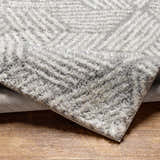 Close-up of the Mura Gray Area Rug showing its shag texture and geometric pattern in beige, gray, and off-white. Fold