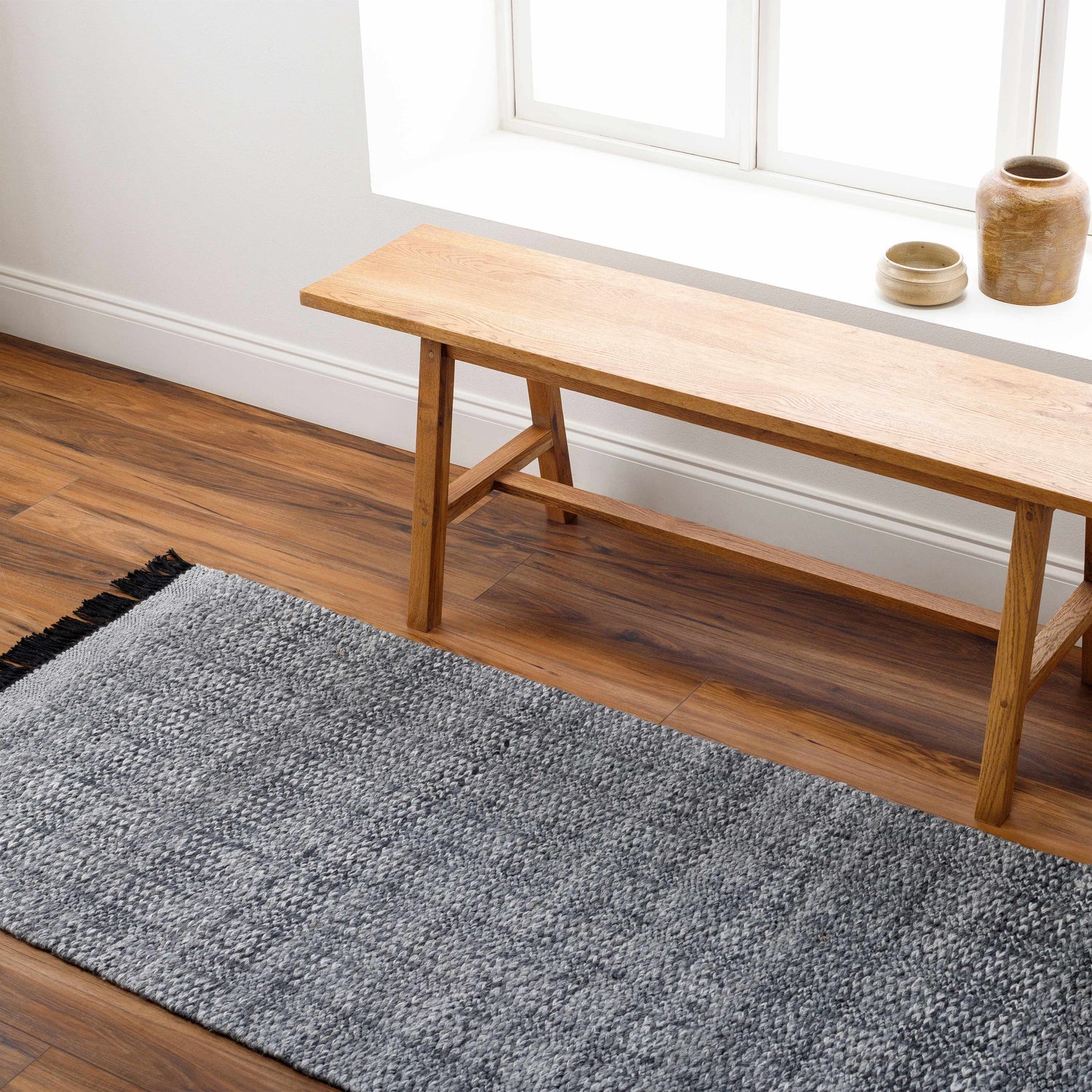 Entryway scene with a light wood bench and Dark Gray Anane Area Rug on wood floors. Roomscene-Runner