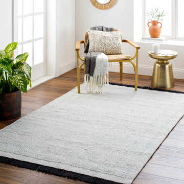 Scandinavian-style room with a light gray Anane Area Rug, gold chair, and side table. Modern, neutral decor. Roomscene-Rectangle