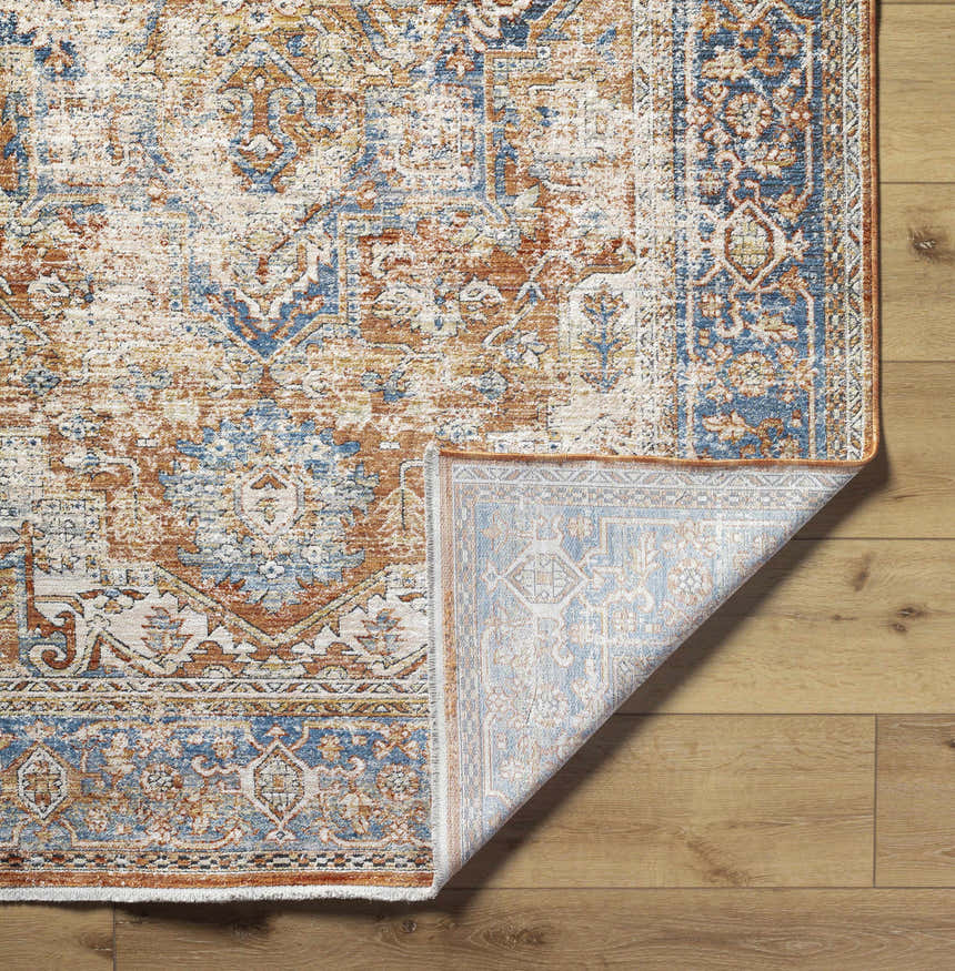 Close-up of the Basim Area Rug showing its bone, charcoal, copper, and rust traditional pattern and machine-woven texture. Fold