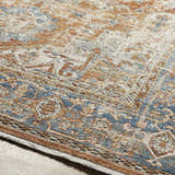 Close up of the Basim Area Rug showing its bone, copper, and blue traditional pattern and soft texture. Texture