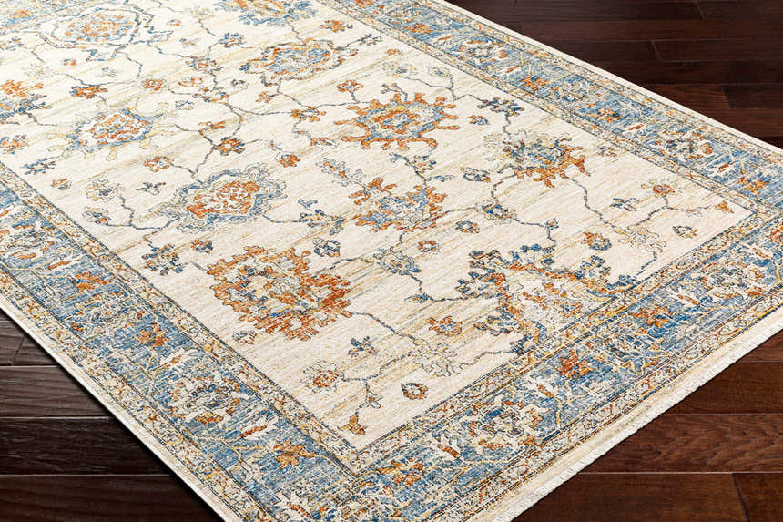 Close-up of the Luma Area Rug featuring a traditional floral pattern in faded driftwood, blue, and orange on a lambswool background. Corner