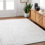 Living room scene with a light beige Kenyi Rose Cream Area Rug, wood floors, console table, and snake plant. Roomscene-Rectangle