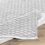 Close-up of the hand woven Scarborough Area Carpet. Gray and white rug with a textured, natural fiber look. Fold