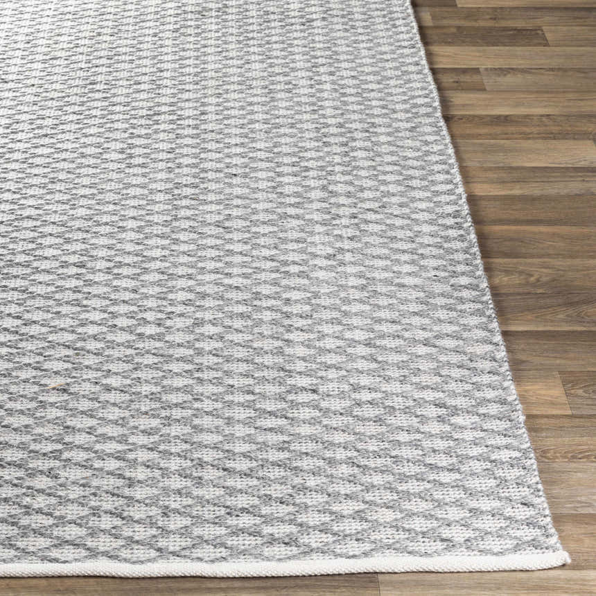 Close-up of the gray and white Scarborough Area Carpet showing its hand woven texture and geometric pattern. Front