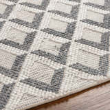 Close-up of the Maik Area Rug, showing gray and light gray geometric pattern and hand-woven texture. Texture