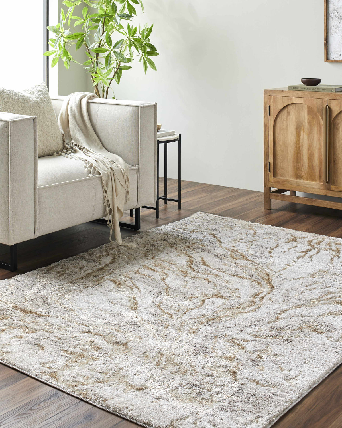 Living room scene with a light silver and warm gray Syler Area Rug, sofa, and wooden cabinet. Roomscene-Rectangle