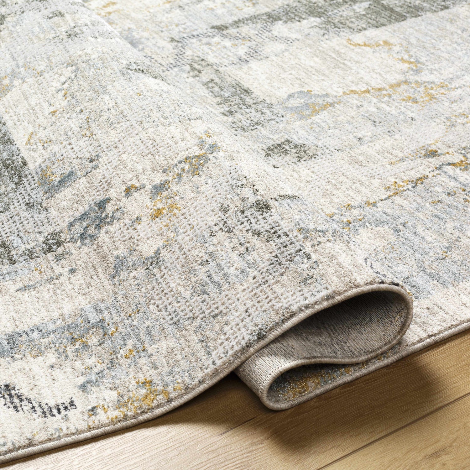 Close-up of the textured Adlai Rug. Colors include off white, gray, blue, and mustard. Contemporary style. Fold