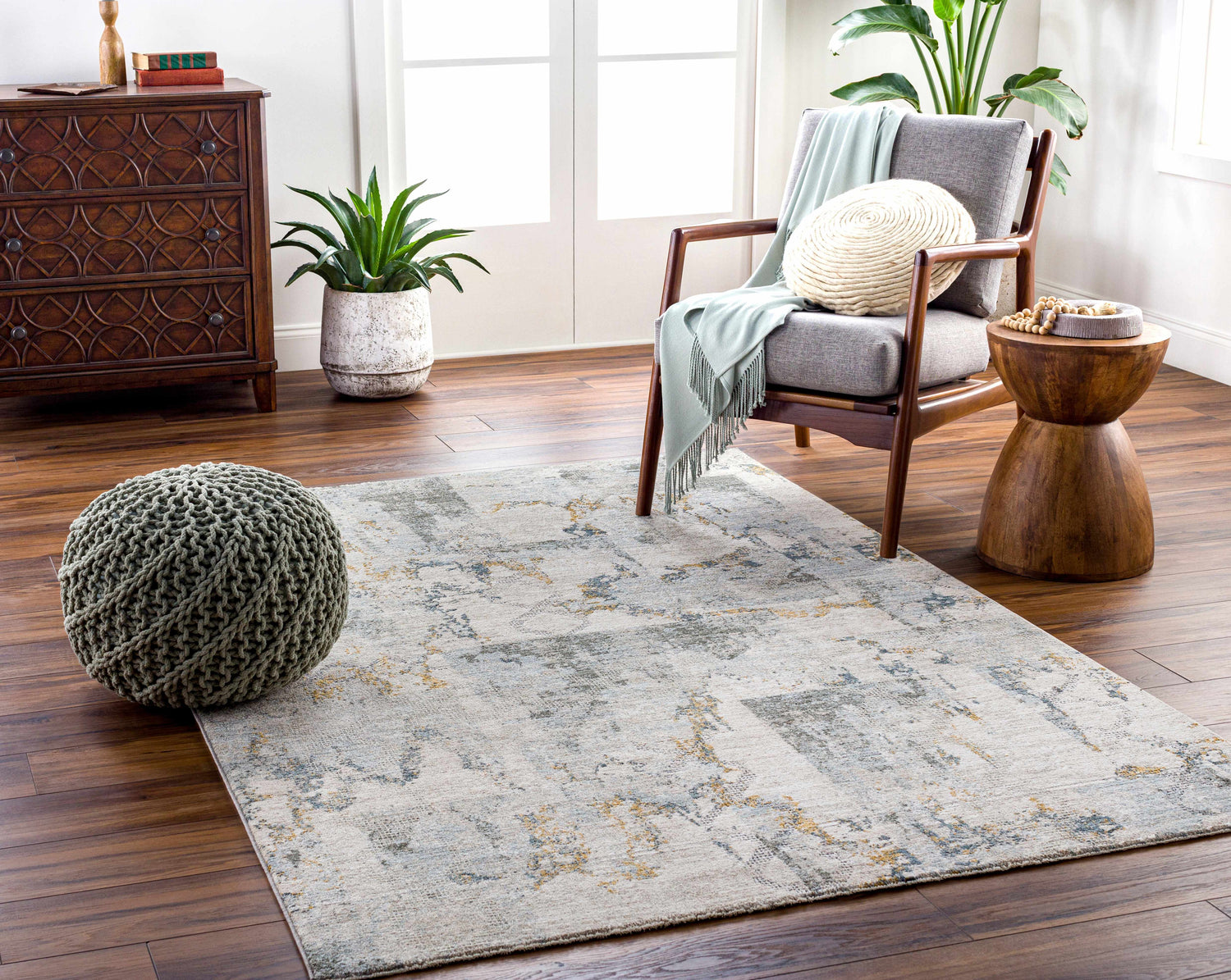 Living room scene with Adlai Textured Rug in light gray, ink blue, and mustard colors. Gray chair, wood accents, and plants. Roomscene-Rectangle