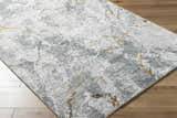 Close-up of the Asena Textured Rug. Abstract pattern in caramel, copper, gray, and brown on a textured polyester rug. Corner