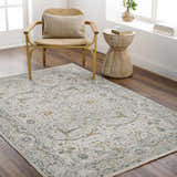 Living room scene with Aviva Off-White Textured Rug, gold chair, and wood side table. Neutral tones and bright natural light. Roomscene-Rectangle