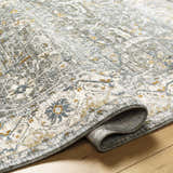 Close-up of textured Aviva Teal Rug. Features dusty sage, light gray, mustard, and off-white traditional pattern. Fold