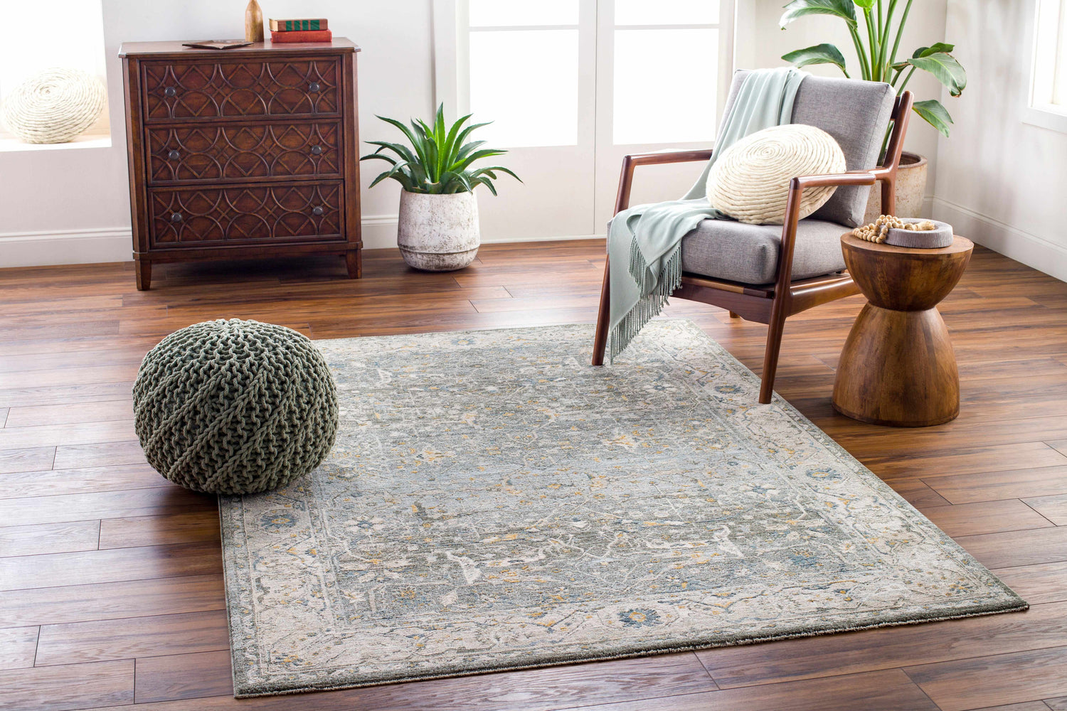 Living room scene with Aviva Teal Textured Rug, gray chair, wood accents, and a sage green pouf. Roomscene-Rectangle