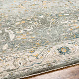 Close-up of the Aviva Teal Textured Rug showing its traditional floral design and textured weave. Colors include teal, mustard, and gray. Texture