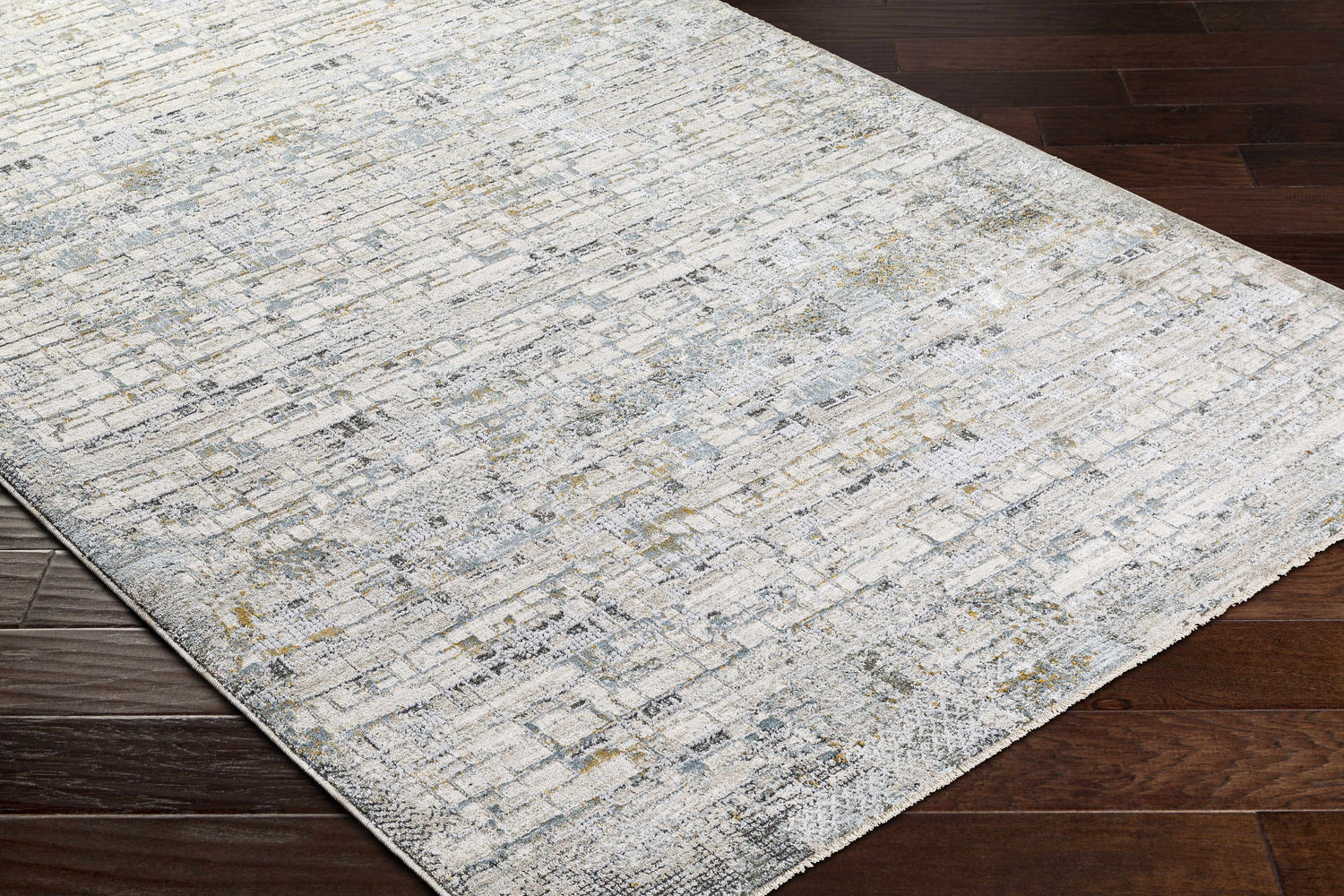 Close-up of the Chaka Textured Rug in off white, light gray, teal, and mustard on a dark wood floor. Corner