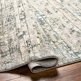 Close-up of the Chaka Textured Rug. Features a contemporary abstract pattern in dusty sage, ink blue, and off-white. Fold