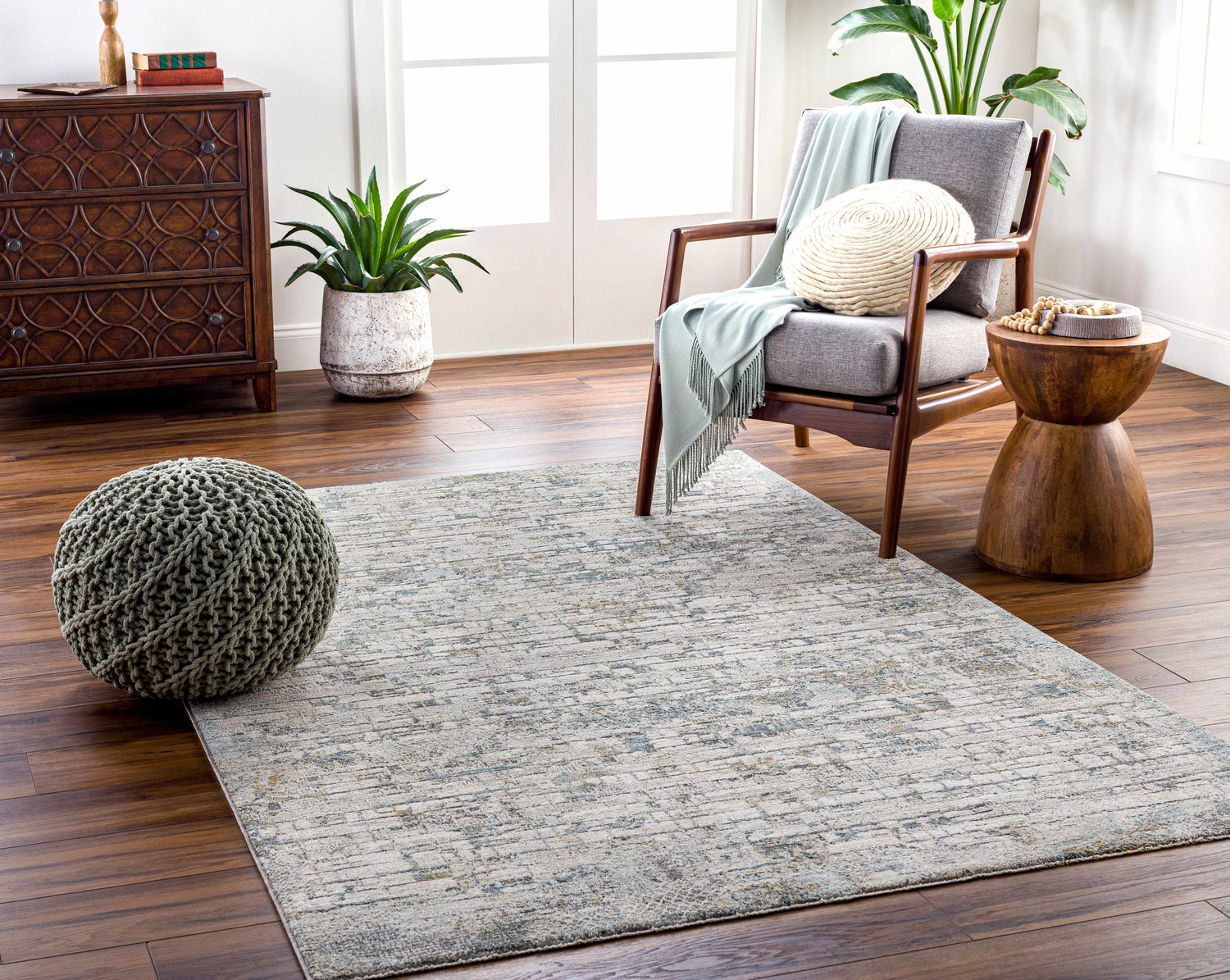 Living room scene with a Chaka Textured Rug, gray armchair, and wooden accents. Roomscene-Rectangle