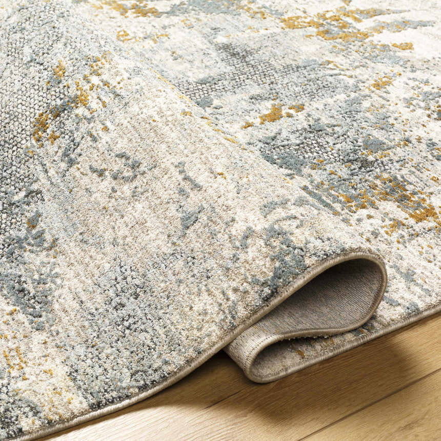 Close-up of the Chaya Textured Abstract Rug. Features dusty sage, ink blue, mustard, and gray colors in a contemporary pattern. Fold