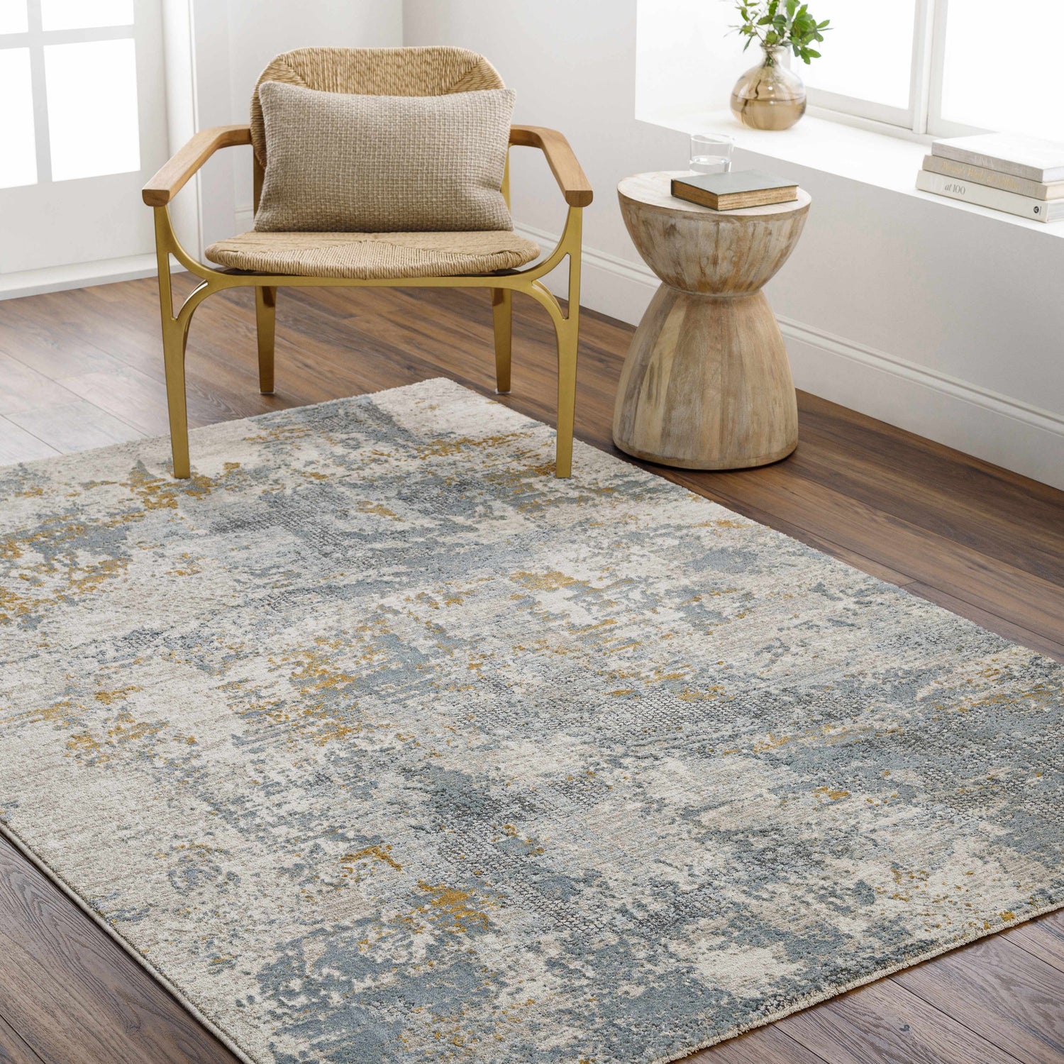 Living room scene with a Chaya Textured Abstract Rug in dusty sage, ink blue, and mustard under a chair and side table. Roomscene-Rectangle