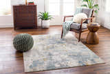 Living room scene with a Chaya Textured Abstract Rug in dusty sage, blue, and gold tones. Mid-century modern style. Roomscene-Rectangle