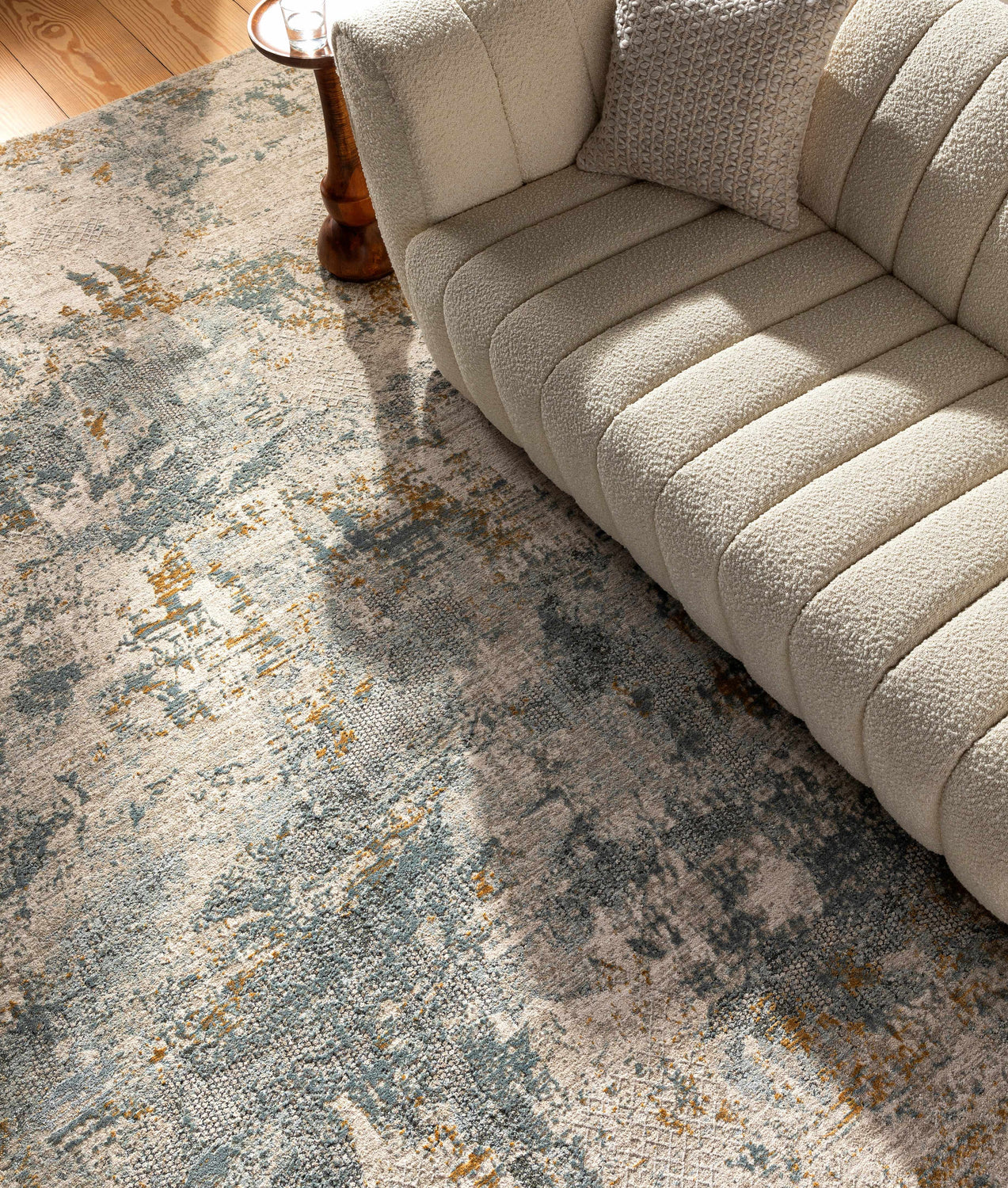 Living room scene with a Chaya Textured Abstract Rug in dusty sage, ink blue, and mustard under a cream boucle sofa. Styleshot