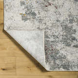 Close-up of the Edana Textured Rug showing its gray, brown, and cream abstract pattern and soft texture. Fold