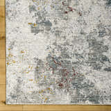 Close-up of the Edana Textured Rug. Cloud gray, dark brown, and gray tones with a distressed contemporary design. Corner