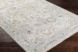 Close-up of the Emile Textured Rug. Off white rug with dusty sage, light gray, and mustard floral pattern on dark wood floor. Corner