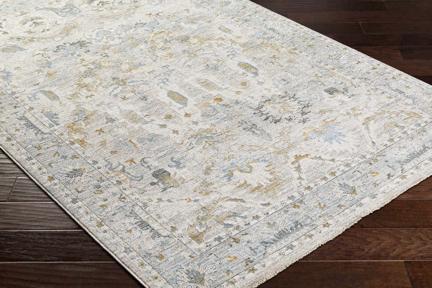 Close-up of the Emile Textured Rug. Off white rug with dusty sage, light gray, and mustard floral pattern on dark wood floor. Corner