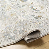 Close-up of the Emile Textured Rug, showing its light gray, taupe, and mustard traditional pattern and soft, textured weave. Fold
