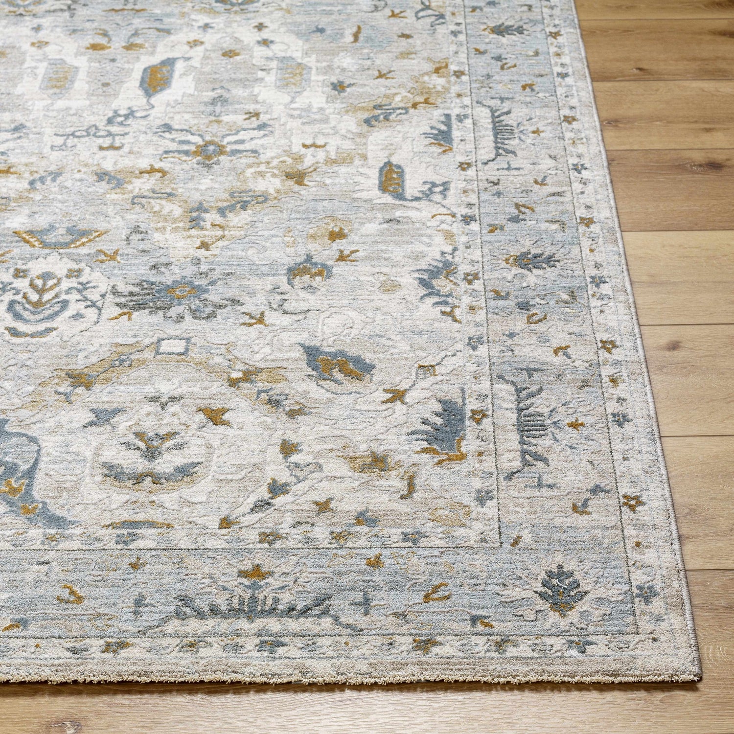 Close-up of the Emile Textured Rug. Features a traditional design in dusty sage, light gray, and mustard tones. Machine woven texture. Front