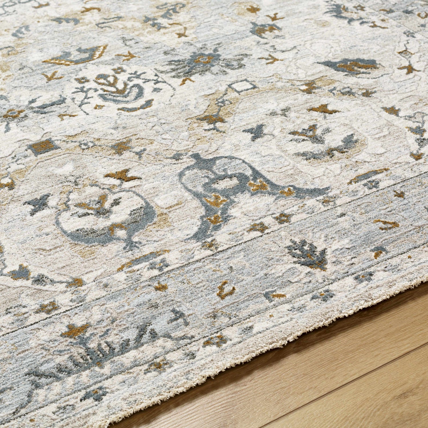 Close-up of the Emile Textured Rug. Features a traditional design in off-white, light gray, and mustard tones. Texture