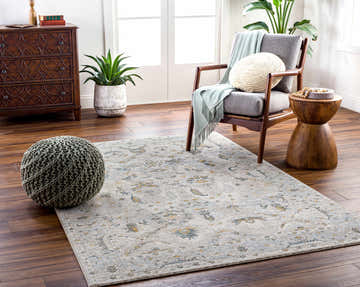 Living room scene with Emile Textured Rug, gray chair, wood accents, and a sage green pouf. Roomscene-Rectangle
