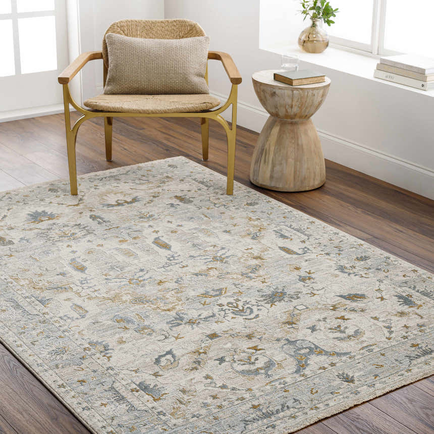 Living room scene with Emile Textured Rug, woven chair, and wood side table. The rug has gray and mustard floral patterns. Roomscene-Rectangle