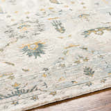 Close-up of the Emile Textured Rug with Fringes. Features dusty sage, light gray, and mustard floral patterns. Texture