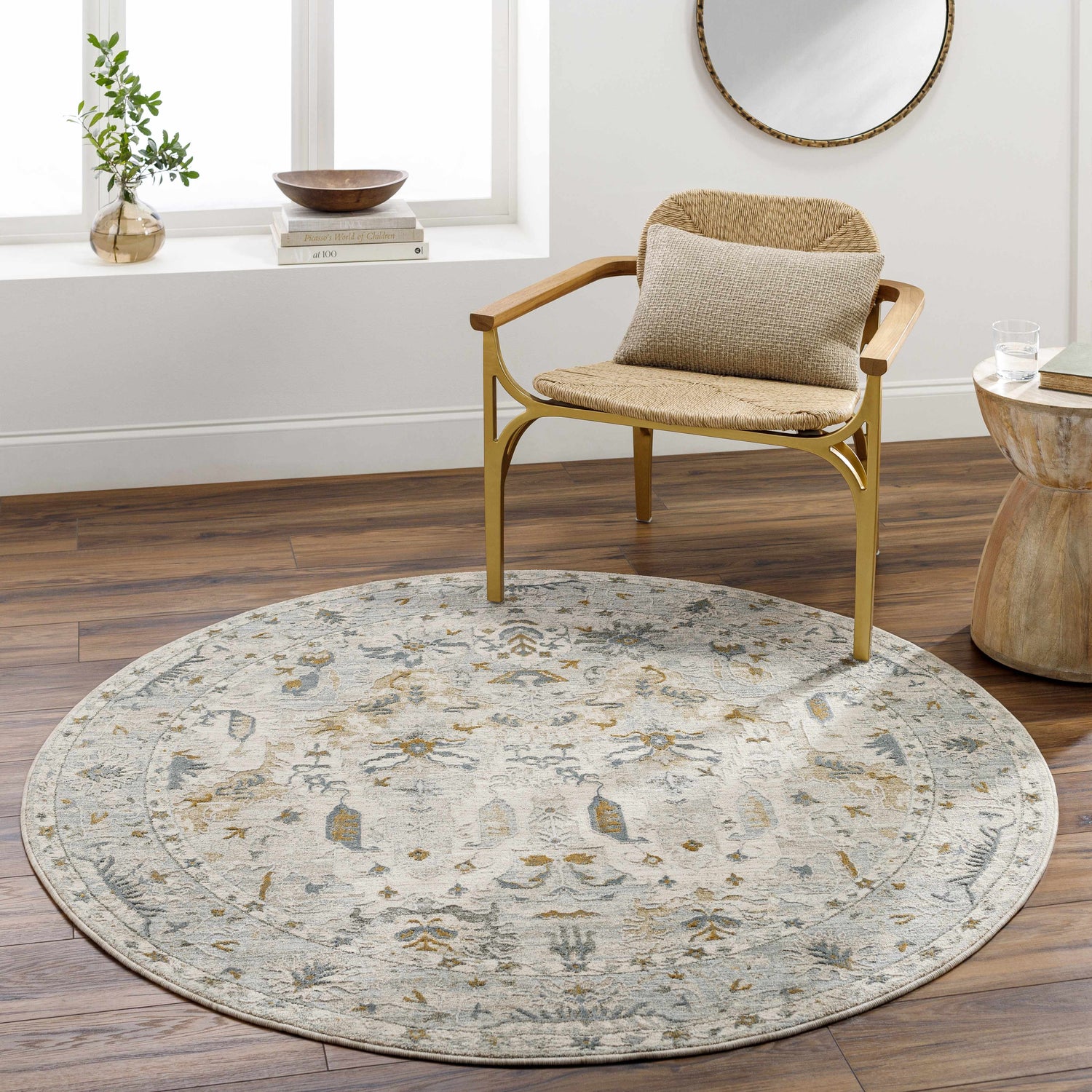 Living room scene with a round Emile Textured Rug in light gray, mustard, and taupe under a chair. Roomscene-Round