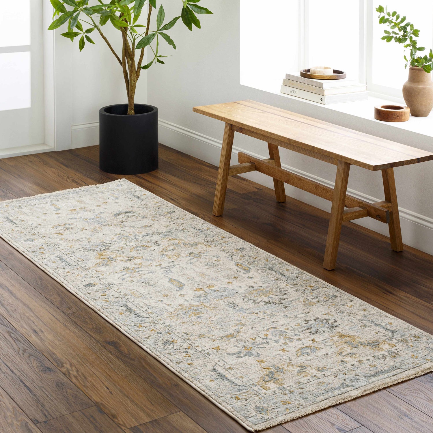 Entryway with wood floors, light wood bench, and a neutral Emile Textured Rug with Fringes. Roomscene-Runner