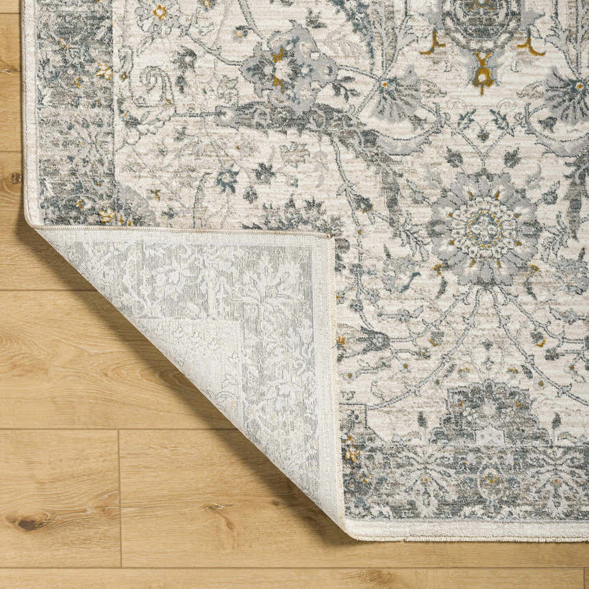 Close-up of the Gauge Cream & Gray Blue Rug showing the traditional floral pattern and the rug's backing. Fold