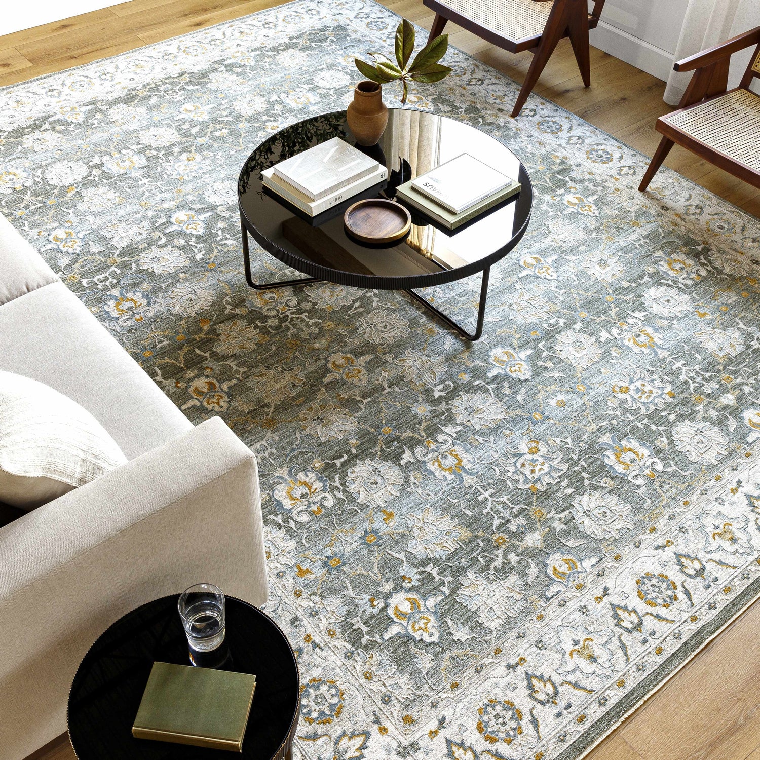 Living room scene with a gray Hafsa Textured Rug, beige sofa, and black coffee table. Roomscene-Rectangle